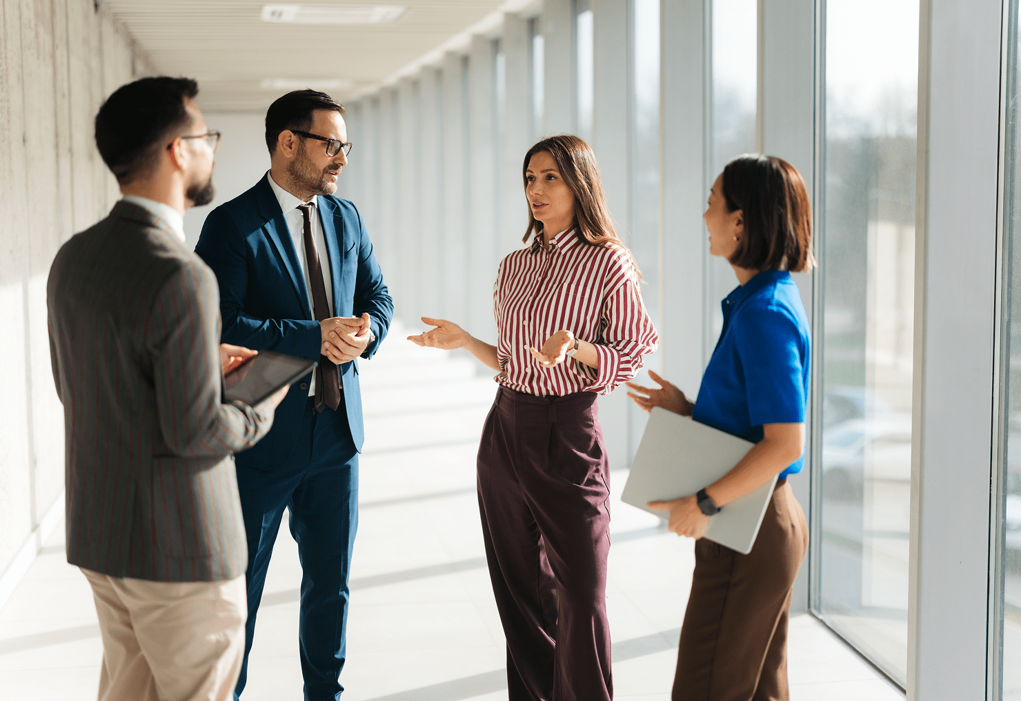 Business meeting in a bright office hallway.
