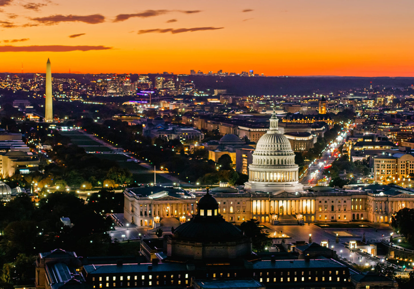 Helicopter shot of the United States Capitol Building with the National Mall and Washington Monument in Washington, D.C. on a clear evening in Fall.